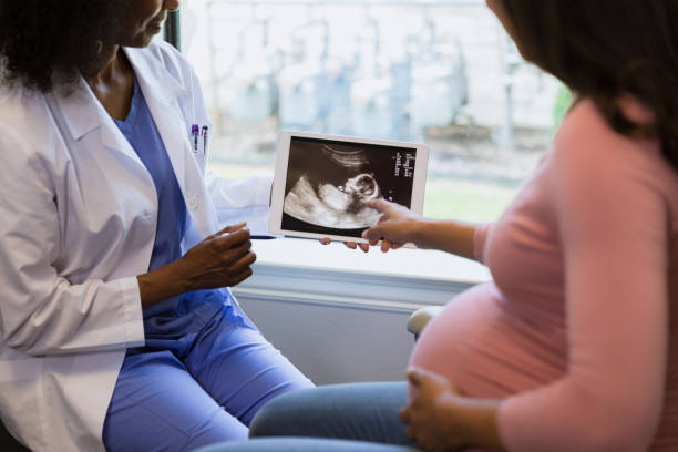 Pregnant patient and doctor reviewing ultrasound scan together.  Healthcare, medicine, technology.
